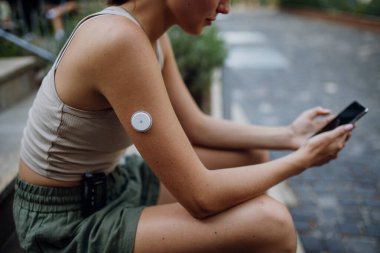 Güzel diyabetik kadın şehir dışında antrenmana hazırlanıyor. İnsülin pompası ve cgm 'si olan genç bir kadın egzersiz yapmadan önce kan şekerini ölçüyor. Egzersiz ve şeker hastalığı kavramı.