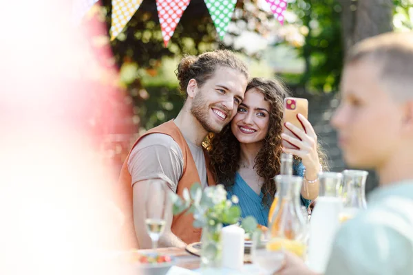 夏のグリルガーデンパーティーでスマートフォンでセルフィーを取るカップル — ストック写真