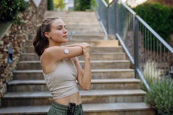 stock image Beautiful diabetic woman preparing for outdoor run in the city. Young woman wearing an insulin pump during exercising. Concept of exercise and diabetes.