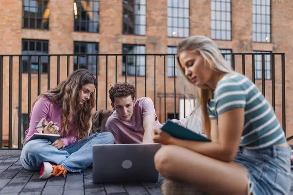 Group of generation Z students studying together outdoors after school. Young stylish zoomers working together on school project, preparing a presentation. Concept of power of friendship and