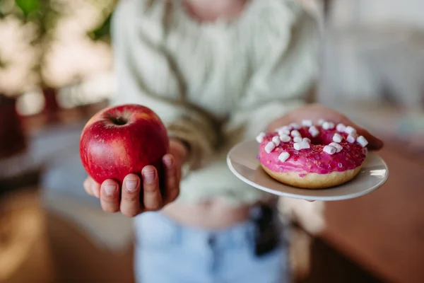 stock image Diabetic woman is choosing between a fresh apple and a sweet doughnut. Importance of proper nutrition and diet in diabetes.