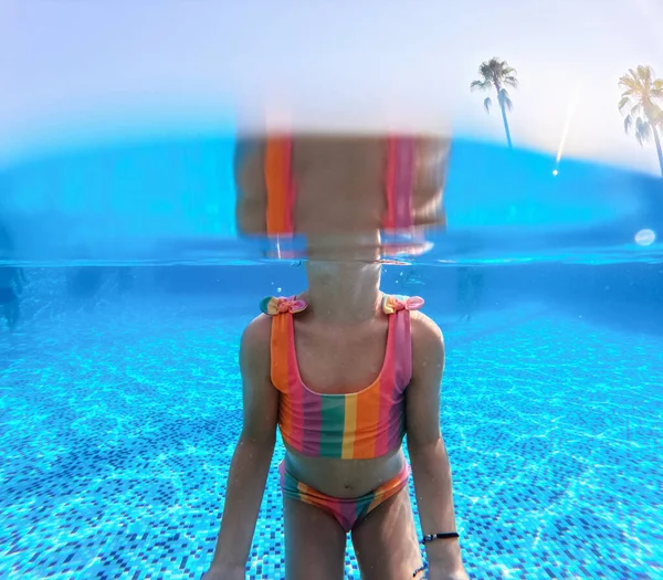 Underwater photography of girl playing in the water in the pool during summer vacation. Winter or summer seaside holiday. Beach resort vacation by the sea.