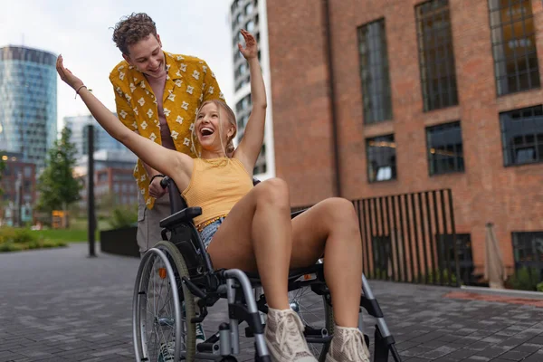 Beautiful smiling gen Z girl in a wheelchair with her boyfriend. Inclusion, equality, and diversity among Generation Z.
