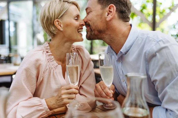 Close up of beautiful couple in a restaurant, on a romantic date. Wife and husband kissing, having a romantic moment at restaurant patio.