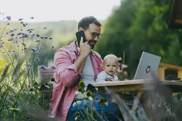 Padre Sosteniendo Bebé Mientras Trabaja Portátil Aire Libre Jardín Empresario —  Fotos de Stock