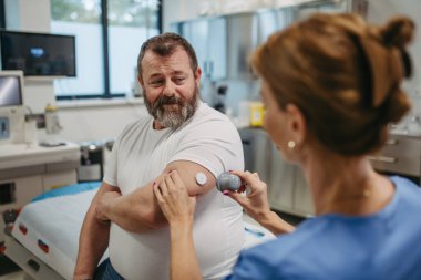 Doktor hasta koluna sürekli glikoz monitörü takıyor. Obez ya da kilolu bir adamın tip 2 diyabet olma riski var. Aşırı derecede obezite ve sağlık riskleri kavramı.