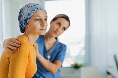 Ergen onkoloji hastası doktorla konuşuyor. Onkolojist, kanserli genç bir kızı tedavi ediyor ve ona duygusal destek veriyor. Endişe ve depresyon konusunda yardımcı oluyor..