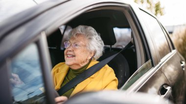 Happy senior woman driving car alone, enjoying the car ride. Safe driving for elderly adults, older driver safety. clipart