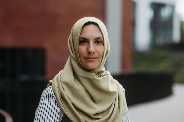 Portrait of beautiful woman in hijab standing on city street.