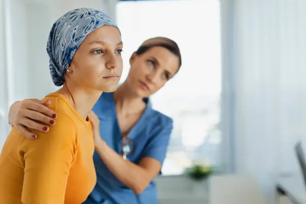 Teenage oncology patient talking with the doctor. Oncologist treating teen girl with cancer and provide emotional support, helping her with anxiety and depression.
