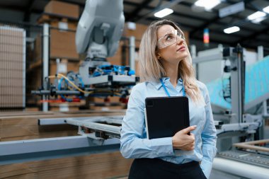Modern endüstriyel fabrikada duran kadın yöneticinin portresi. Robot ve otomasyonlu üretim tesisi. Kadın lider, ağır sanayi CEO 'su, imalat..