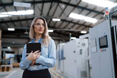 Modern endüstriyel fabrikada duran kadın yöneticinin portresi. Robot ve otomasyonlu üretim tesisi. Kadın lider, ağır sanayi CEO 'su, imalat..