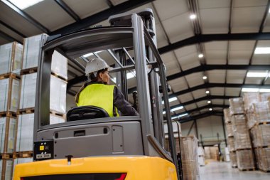 Forklift kullanan kadın depo işçisinin portresi. Depo işçisi nakliye, teslimat ve depodaki stokları kontrol etmek için ürünler hazırlıyor..
