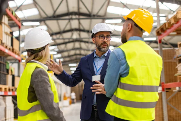 stock image Engineers consulting with director in modern industrial factory, talking about new production project, investment. Team management in manufacturing facility.