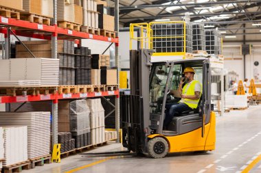 Forklift kullanan erkek bir depo çalışanı. Depo çalışanı nakliyat, teslimat, depodaki stokları kontrol etme, sipariş toplama için ürünler hazırlıyor..