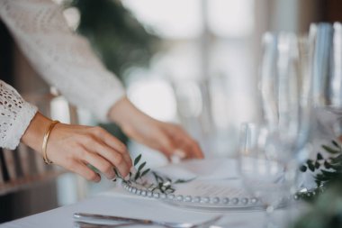 Kadın hazırlığı, kapalı mekan düğün resepsiyonu için romantik masa hazırlama, kutlama. Lüks düğün masası dekorasyonu, taze çiçeklerle hazırlanmış özel bir etkinlik masası..