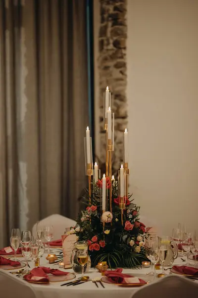 Elegant, romantic table setting for indoor wedding reception, celebration. Luxury wedding table decoration, special event table set up with fresh flowers arragements and high candlestick, candle