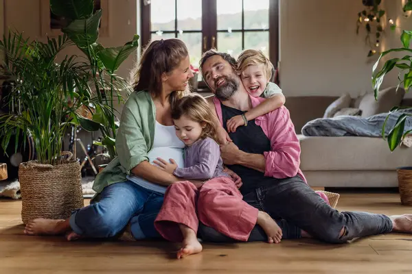自宅にいる若い家族の肖像 リビングルームで彼女の子供と夫と妊娠した母親 — ストック写真