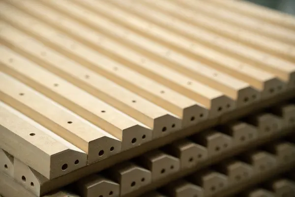 Close up of wooden parts in in big furniture manufacturing facility. Wooden parts for the production of chairs, tables or beds in the warehouse of a furniture factory.