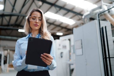 Modern endüstriyel fabrikada duran kadın yöneticinin portresi. Robot ve otomasyonlu üretim tesisi. Kadın lider, ağır sanayi CEO 'su, imalat..