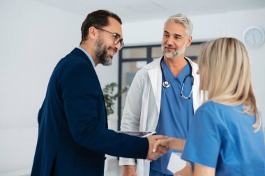 İlaç satış temsilcisi tıp binasındaki doktorlarla konuşuyor. Yeni ilaç ürünlerini denemesi ve el sıkışması için onu mahkum ediyor. Doktor ilaç örnekleriyle dolu bir kutu tutuyor..