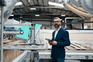 Modern endüstriyel fabrikada erkek mühendis, robotik kolu kontrol ediyor, süreci kontrol ediyor ve ekipman ve makine üretiyor. Robotlarla üretim tesisinde kalite güvence müfettişleri.