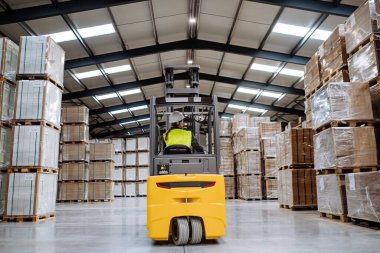 Forklift kullanan kadın depo işçisinin portresi. Depo çalışanı nakliye, teslimat ve depodaki stokları kontrol etmek için ürünleri topluyor ve hazırlıyor..