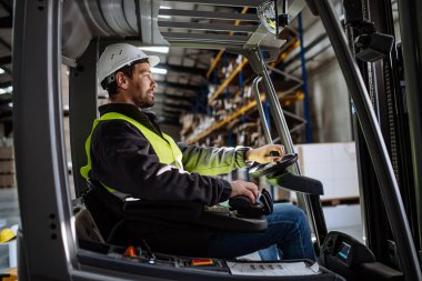 Forklift kullanan çok ırklı depo işçisinin portresi. Depo işçisi nakliye, teslimat ve depodaki stokları kontrol etmek için ürünler hazırlıyor..