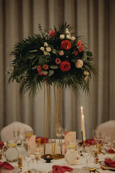 Elegant, romantic table setting for indoor wedding reception, celebration. Luxury wedding table decoration, special event table set up with fresh flowers arragements on high stands.