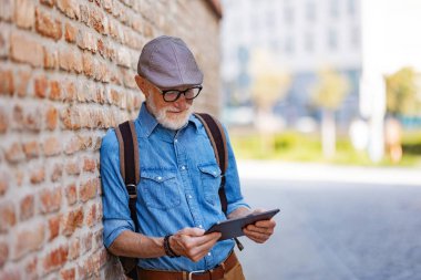 Yaşlı turistlerin yeni bir şehri keşfetmesinin yan görüntüsü, ilginç yerler. Tablet tutan yaşlı adam, yolu arıyor. Emeklilikte seyahat ve tek kişilik geziler.