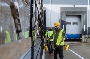 Depo alıcıları teslimat malzemelerini kontrol etmek için kamyoneti deponun önünde boşaltıyor. Kargo boşaltılıyor.