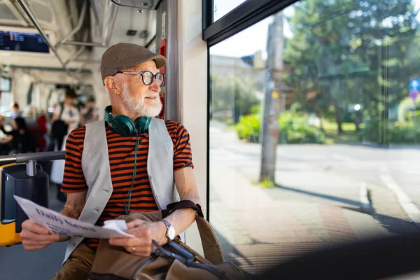 高齢者がバスで街を旅し 新聞を読んでいる 公共交通機関を使用して 食料品店にトラムを取るシニア都市通勤者 — ストック写真