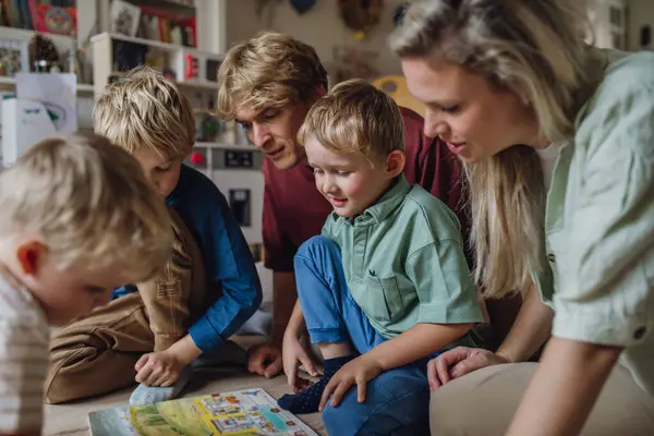 3人の子供がリビングルームで本を読み フロアで一緒に楽しんでいる陽気な家族 — ストック写真