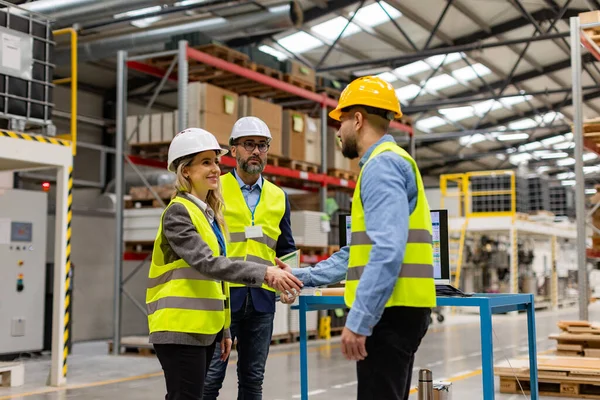 stock image Engineers shaking hands with foreman in modern industrial factory, talking about new production project, investment. Team management in manufacturing facility.