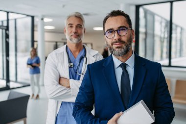 Hastane koridorunda duran ilaç satış temsilcisinin portresi. Hastane müdürü, hastane lobisindeki özel sağlık kliniğinin müdürü. Doktor arkasında duruyor..