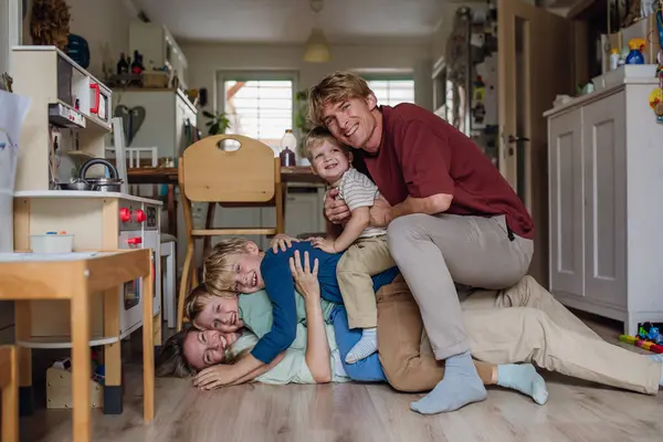 家族の肖像画は リビングルームで互いの床に横たわって楽しんで座っています 彼女の3人の息子と夫がカメラを見て笑っている美しい母親 — ストック写真