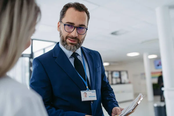 Portrait of pharmaceutical sales representative talking with doctor in medical building. Ambitious male sales representative in suit presenting new medication. Hospital director, manager in private