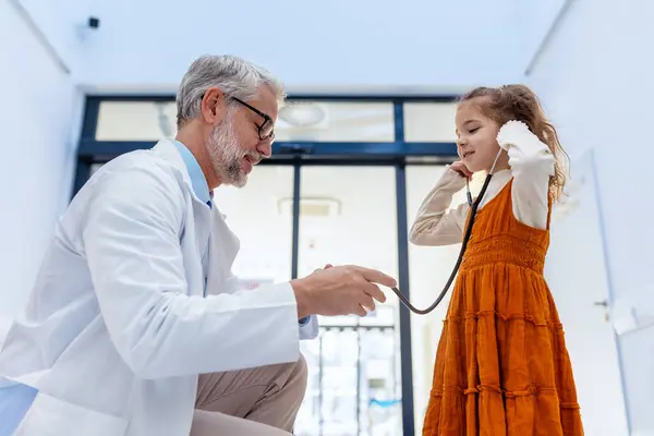 小女孩用听诊器听医生的心脏 角色转换 医生与儿童病人之间的友好关系 — 图库照片