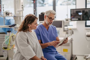 Doktor tablette kadın MRI taraması gösteriyor. Acil serviste test sonuçlarını tartışıyor..
