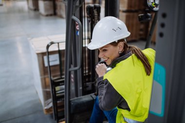 Forklift kullanan kadın depo işçisinin portresi. Depo işçisi nakliye, teslimat ve depodaki stokları kontrol etmek için ürünler hazırlıyor..