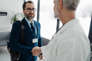 İlaç satış temsilcisi tıbbi binada doktorla el sıkışıyor. Doktor, hastane müdürü, özel sağlık kliniğinde müdür..