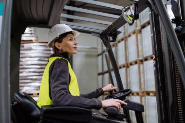 Forklift kullanan kadın depo işçisinin portresi. Depo işçisi nakliye, teslimat ve depodaki stokları kontrol etmek için ürünler hazırlıyor..