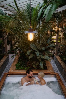 Güzel, olgun bir çift jakuzide dinleniyor, şampanya içiyor, kaplıcada romantik sağlık haftasonunun tadını çıkarıyor. Sevgililer Günü Konsepti.