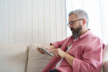 Adam akıllı termostat kullanıyor, ısıyı ayarlıyor, evdeki ısıyı düşürüyor. Tablet 'te TV şovu izleyen adam, çevrimiçi sinema ve televizyon programlarıyla video yayınlama hizmetleri.