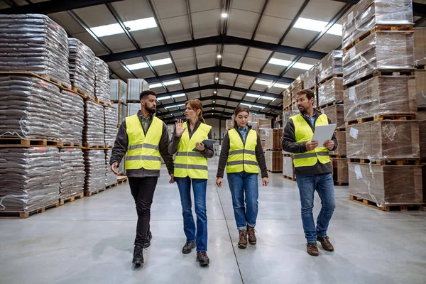 Full team of warehouse employees walking in warehouse. Team of workers in reflective clothing in modern industrial factory, heavy industry, manufactrury. Group portrait.