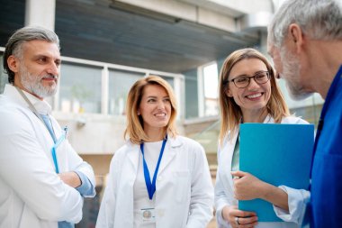 Doktorlar hastane koridoruna girip gülümsüyor. Meslektaşlar ve doktorlar hasta teşhisini tartışıyor.