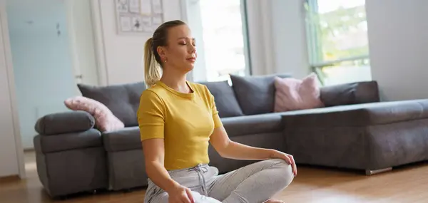 Woman exercising at home, stretching body. Single woman is happy, relaxed, and content with her life. Solo home workout and meditation, morning or evening workout routine. Banner with copyspace.