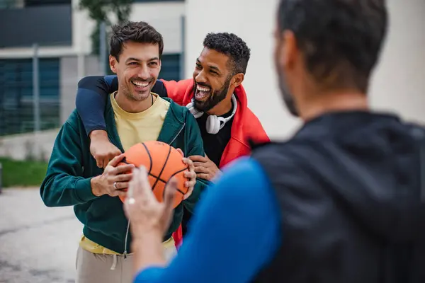 Best friends playing sport outdoors, having fun, competing. Playing basketball at local court, enjoying exercise together. Concept of male friendship, bromance.