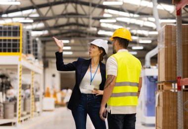 Kadın yönetici modern endüstri fabrikasında çalışanı azarlıyor. İşçi hata yapıyor. Üretim görevlisi kızgın, işçiler için tatminsiz kalitesiz iş ve güvenlik ihlalleri.