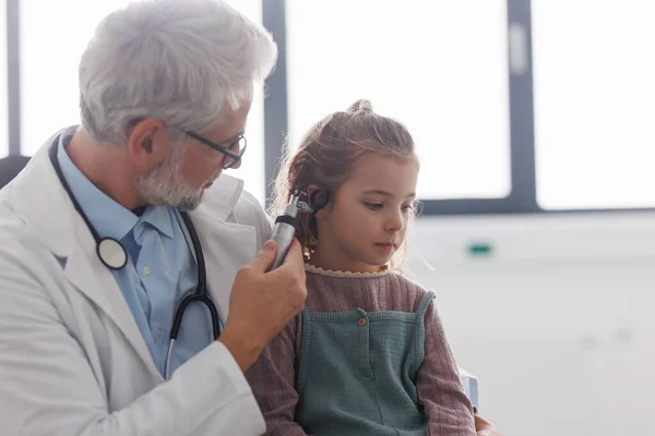 医生用耳镜检查小女孩的耳朵 寻找感染 医生与儿童病人之间的友好关系 — 图库照片